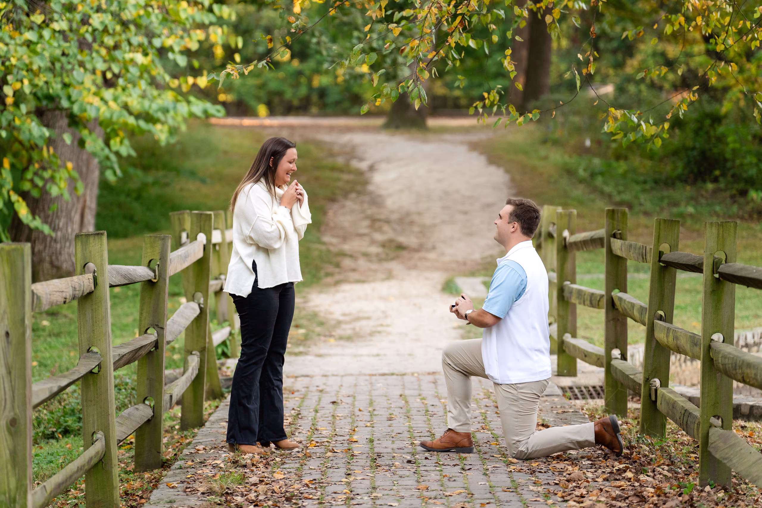 Man proposing on bridge, woman reacts with joy