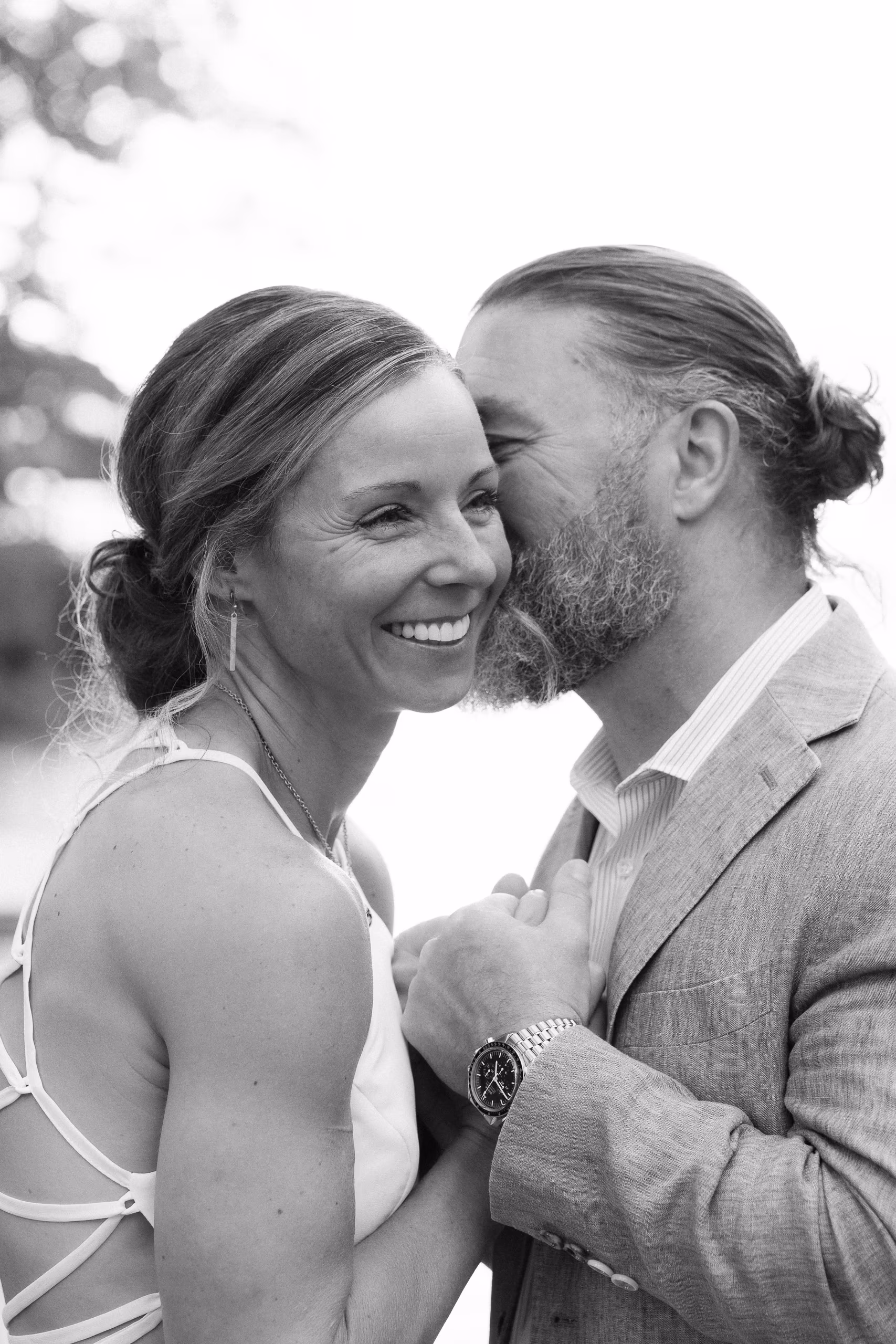 Happy couple embracing; man whispering to smiling woman.