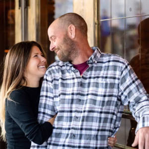 Happy couple smiling at each other, woman embracing man in plaid shirt