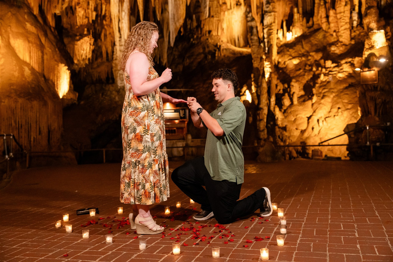 Man proposes to woman in Luray Caverns Cathedral Room with candles and rose petals.