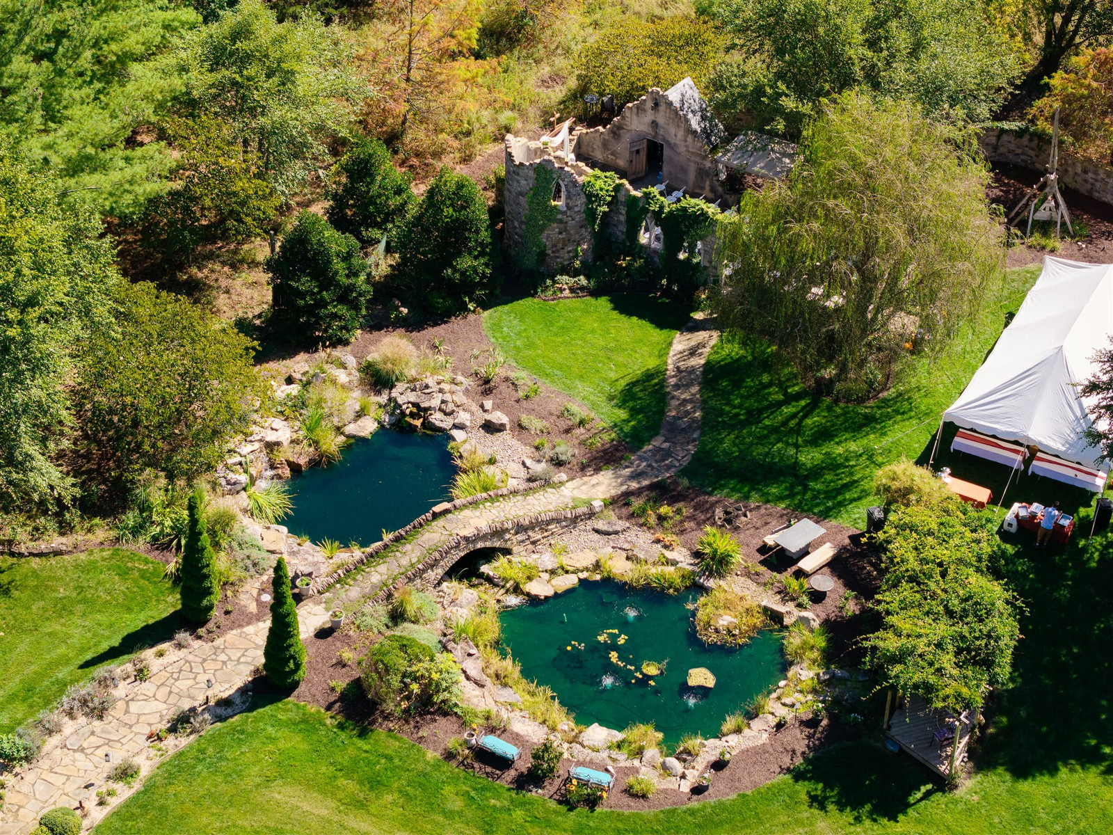 Aerial view of Brenden and Selena's wedding venue with ponds, stone bridge, ruins, and tent in Grottoes, VA.